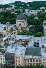From above the Dominican Church in Lviv Ukraine stands out with its distinctive dome surrounded by the old city's buildings and trees offering a picturesque overview of the historical significance.