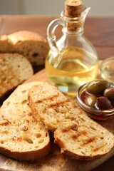 Toasted bread with oil and olives on table, closeup