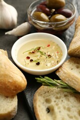 Sliced bread with oil, olives and spices on black table, closeup
