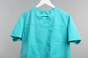 Medical worker uniform on hanger against grey background