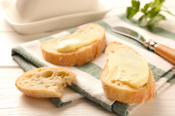 Slices of bread with butter on white wooden table, closeup