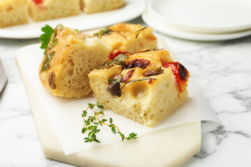 Pieces of delicious focaccia on white marble table, closeup