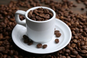 Aromatic coffee beans, cup and saucer on table, closeup