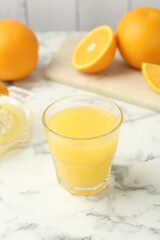 Fresh orange juice and fruits on white marble table, closeup