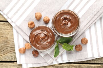 Tasty chocolate spread, hazelnuts and mint on wooden table, top view