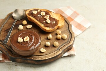 Toasts with tasty chocolate spread and hazelnuts on light table, closeup
