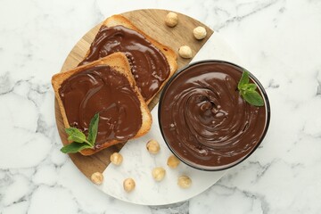 Tasty chocolate spread with mint and hazelnuts on white marble table, top view