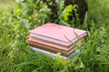 Stacked books on green grass outdoors, closeup
