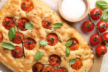 Delicious focaccia with tomatoes and spices on table, flat lay