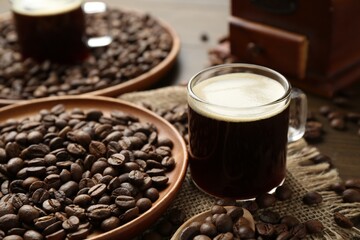 Aromatic coffee in cup and beans on table, closeup
