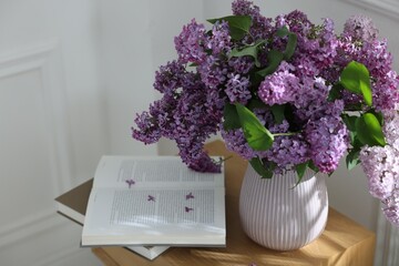 Bouquet of beautiful lilac flowers and books on wooden table
