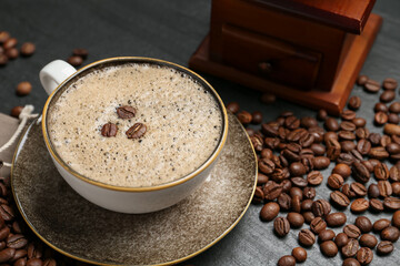 Aromatic coffee in cup, beans and grinder on black table, closeup