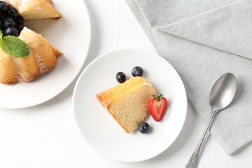 Tasty bundt cake with powdered sugar, berries and mint on white table, flat lay