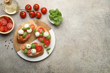 Tasty sandwiches with mozzarella cheese balls, tomato and basil on grey table, flat lay. Space for text