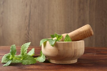 Fresh lemon balm leaves, pestle and mortar on wooden table, closeup