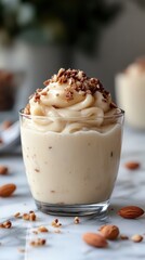 Creamy dessert topped with nuts served in a glass on a marble countertop in a cozy kitchen setting