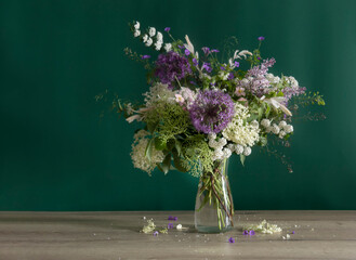 wildflowers in glass vase  on green background