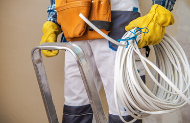 Construction Worker Prepares for Electrical Installation While Holding Tools and Ladder Indoors