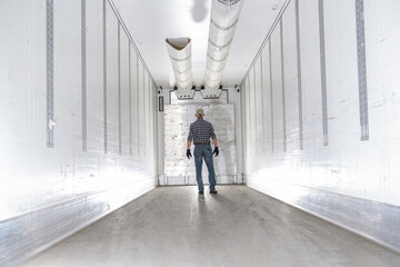 Worker Standing Inside a Refrigerated Truck Trailer Inspecting the Interior for Cleanliness and...