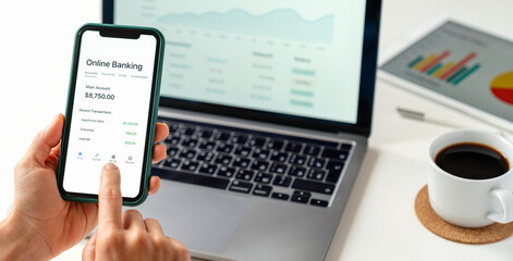 User making financial transaction using online banking app on smartphone and laptop
