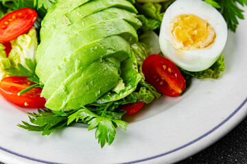 Salad avocado, egg, tomato, green leaf lettuce, vegetable dish fresh gourmet food background on the table rustic food top view copy space keto and paleo diet vegetarian food
