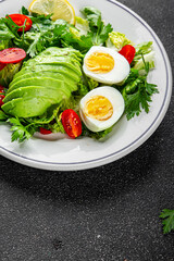 Salad avocado, egg, tomato, green leaf lettuce, vegetable dish fresh gourmet food background on the table rustic food top view copy space keto and paleo diet vegetarian food