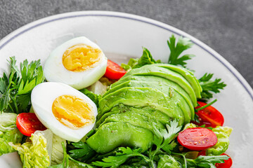 Salad avocado, egg, tomato, green leaf lettuce, vegetable dish fresh gourmet food background on the table rustic food top view copy space keto and paleo diet vegetarian food