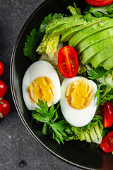 Salad avocado, egg, tomato, green leaf lettuce, vegetable dish fresh gourmet food background on the table rustic food top view copy space keto and paleo diet vegetarian food
