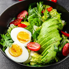 Salad avocado, egg, tomato, green leaf lettuce, vegetable dish fresh gourmet food background on the table rustic food top view copy space keto and paleo diet vegetarian food