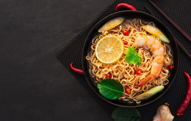 Top view of ramen instant noodle soup with shrimp in black bowl on black background. Asia Food, Tom Yum Kung