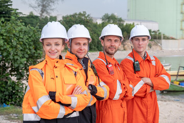 Team of workers in safety gear posing confidently at a coastal worksite during daylight