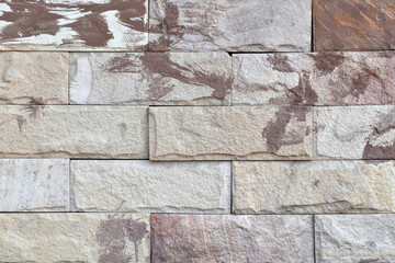 sandstone brick wall with paint stains, row of rough textured stone block