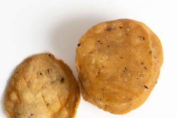 Stack of mathri, or Mathi an Indian a flaky biscuit savoury snack made with all-purpose flour, wheat  flour on white backgropund. Top view.