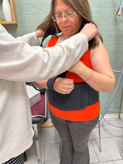 Female adult patient assisted by orthopedic specialist, Woman with shoulder bandage, Orthopedic arm sling, post-surgery support