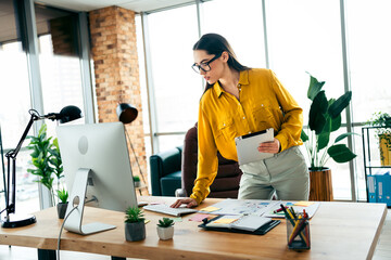 Young business professional in modern office workspace working on project with a thoughtful...