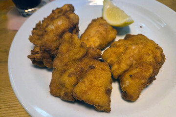 Crispy Fried Chicken Pieces with Lemon Garnish on White Plate