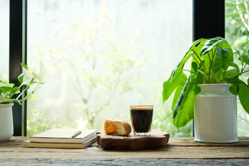 Coffee and bread with Philodendron plant and pothos by the window