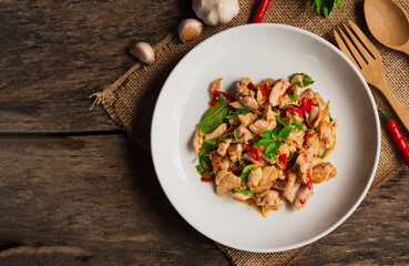 Top view of stir fried chicken with basil and chili in white plate on wooden background. Thai Food