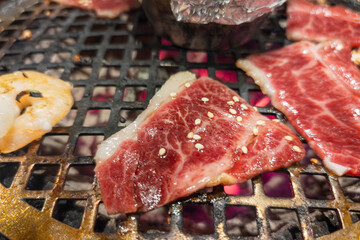 焼肉の網の上で焼かれる霜降り肉と海鮮のクローズアップ