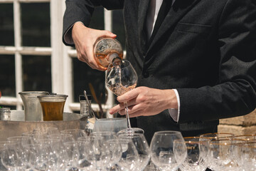 Gentleman in tuxedo pouring Rose wine in the sunshine