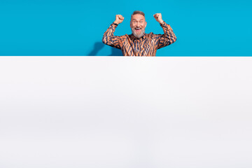 Charismatic Mature Man in Stylish Print Shirt Celebrating Against Blue Background