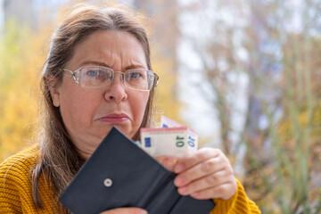 disappointed white woman 50 years old, presenting, counts euro banknotes in hand, cash payments, savings, exchange and cashing currency, financial freedom
