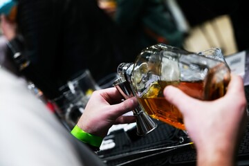 Pouring a rich amber brew at a vibrant craft beer festival ambiance