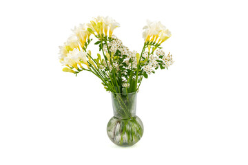White and yellow freesias stand in a fluted glass vase. A simple floral arrangement on a white background.