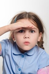 Young girl looking intently into the distance, shielding her eyes with her hand.