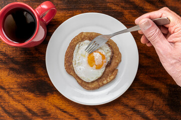 Breaded sausage with fried egg on a plate, fork, hand, breaded, breaded, battered, coffee,