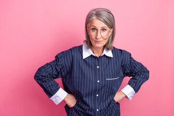 Confident mature businesswoman showing a firm pose, wearing a striped blouse, with a vibrant pink...