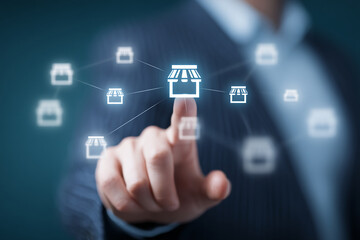 Obraz premium Hand interacts with digital network of store icons, illustrating online business expansion and connection, showcasing a concept of multi-store management