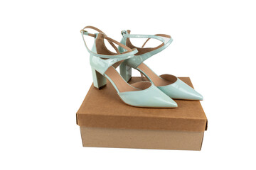 Elegant mint green high heels stand on a closed shoebox. The shoes shine with their patent leather and appear high-quality. Shoes on a box isolated on white background