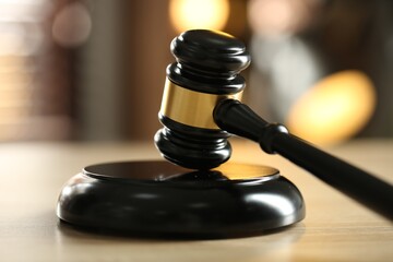 Judge's gavel on wooden table against blurred background, closeup